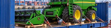 John Deere combine secured on a flat rack for ocean transport